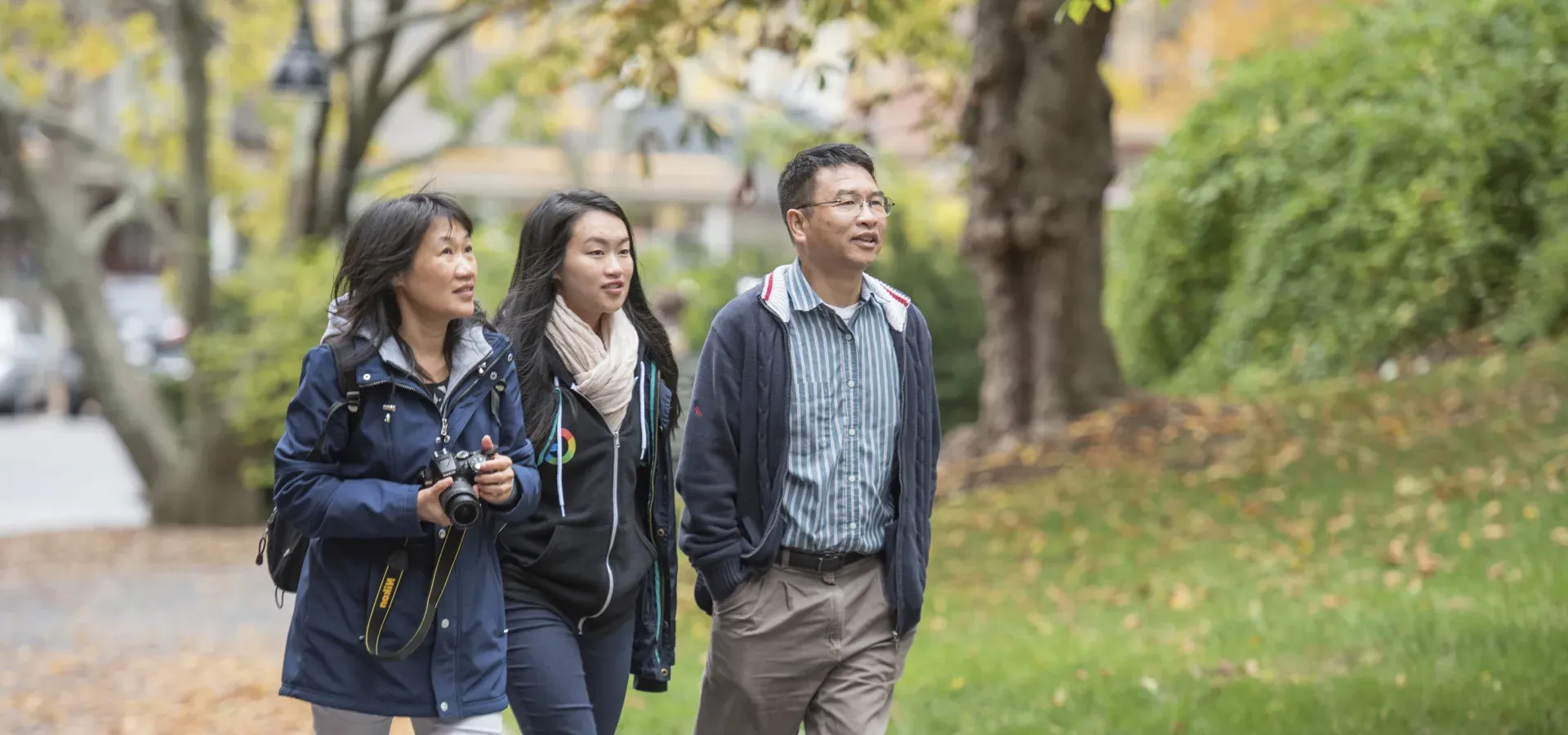 一个学生和他们的家人走在校园里.