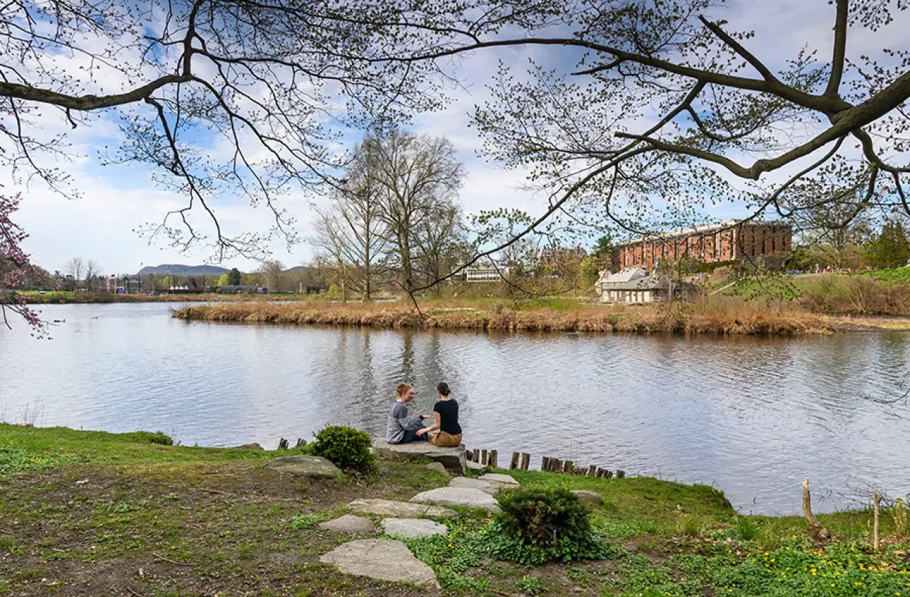 Two students sitting by Paradise Pond