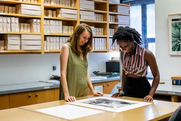 A student and supervisor looking at a photo on a table.